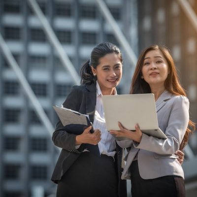 portrait smiling colleagues with laptop standing against building city 1599898 1239
